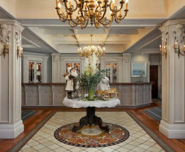 Elegant hotel lobby with chandeliers, grand reception, festive decorations, warm lighting, welcoming atmosphere.