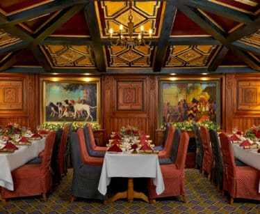 Elegant hotel dining room with plush red chairs, ornate wooden decor, and ambient lighting offering a luxurious dining experience.