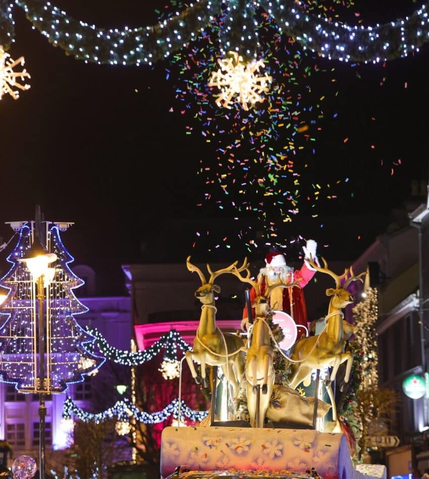 Festive winter street with Santa sleigh, reindeer, twinkling lights, snowflakes, perfect for holiday stays.