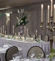Elegant banquet hall set for a wedding with candlelit tables, fine china, and floral arrangements in a luxury hotel.