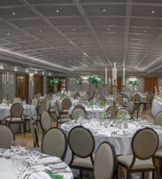 Elegant hotel ballroom with round tables, chic lighting, floral centrepieces, perfect for banquets and weddings.