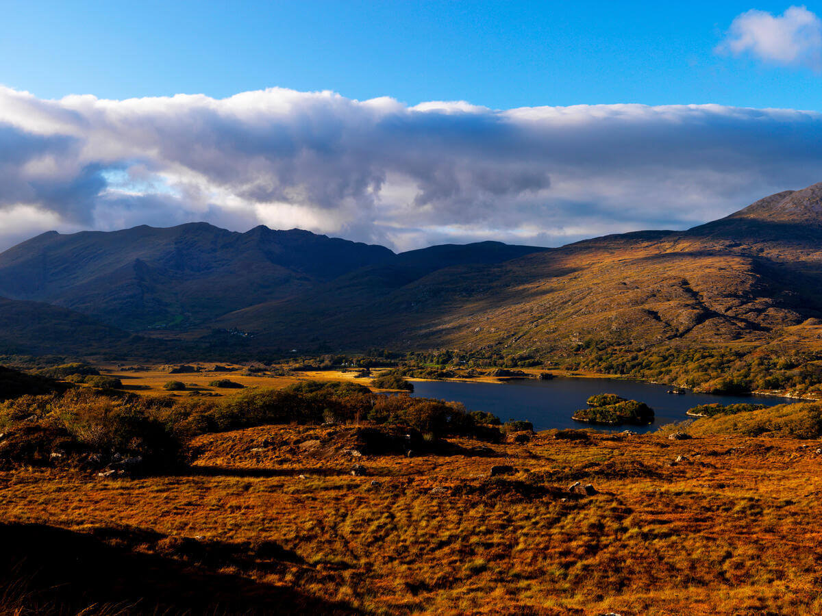 Guests enjoy stunning mountain and lake views under blue skies, perfect for a peaceful retreat in Irish nature.
