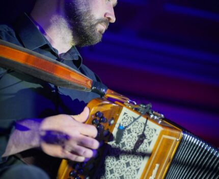 Musician performing with a button accordion at the Gaelic Roots Irish music and dance showcase.