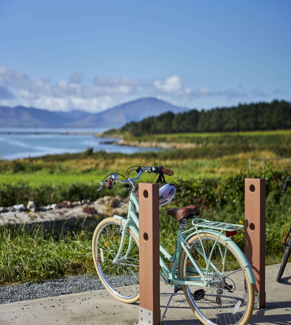 Scenic coastal view with mountains and a parked bicycle, ideal for biking enthusiasts; lush greenery and blue skies.