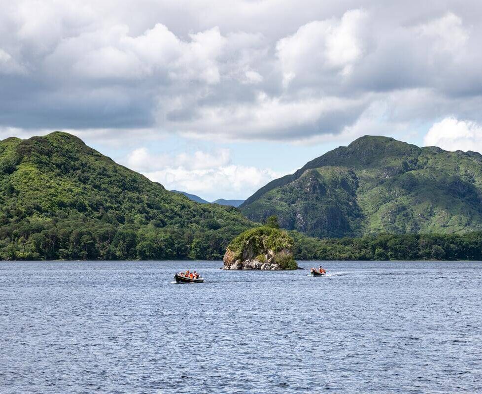 Guests enjoy scenic lake views with lush green hills and blue sky, ideal for tranquil getaways near elegant hotel retreats.