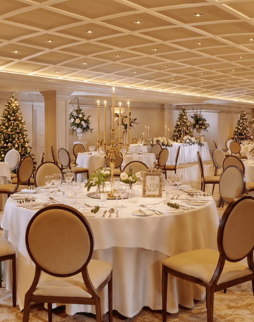 Elegant hotel banquet hall with festive decorations, round tables, and soft lighting, ideal for events and celebrations.